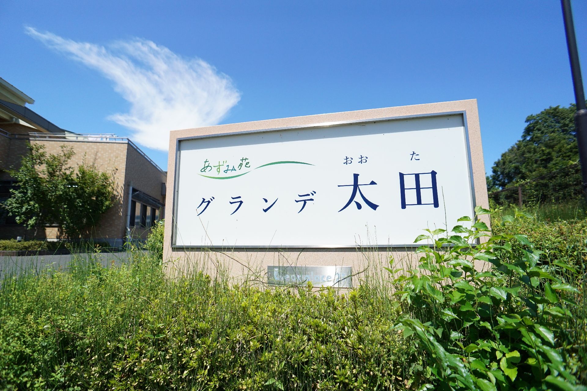 緑の植物の中に配置されたあずみ壮グランデ太田と書かれた看板