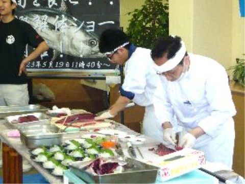 入居者に向けてマグロの解体ショーを行っている料理人
