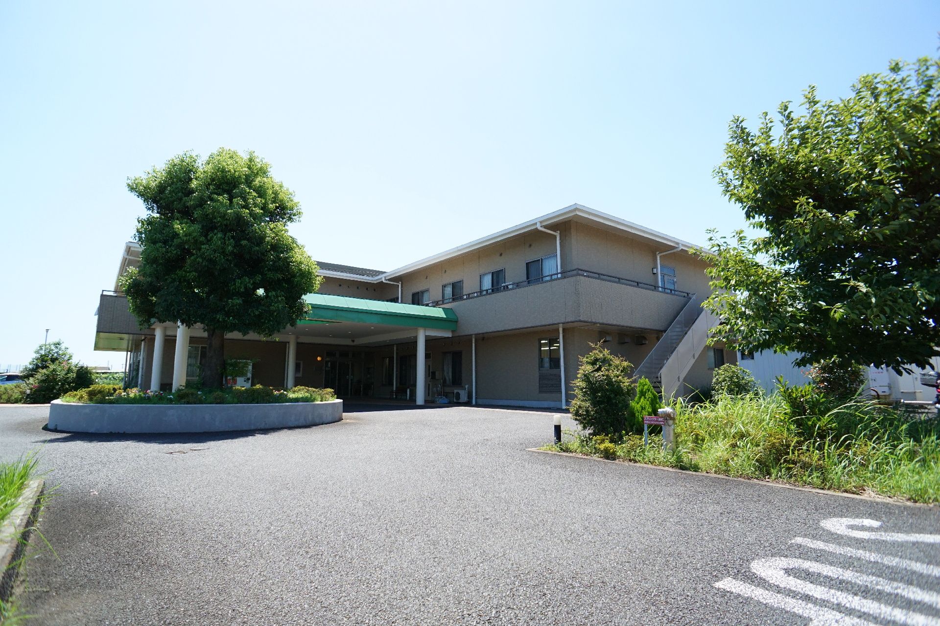 アスファルトに隣接した２階建てでベージュの外観の建物