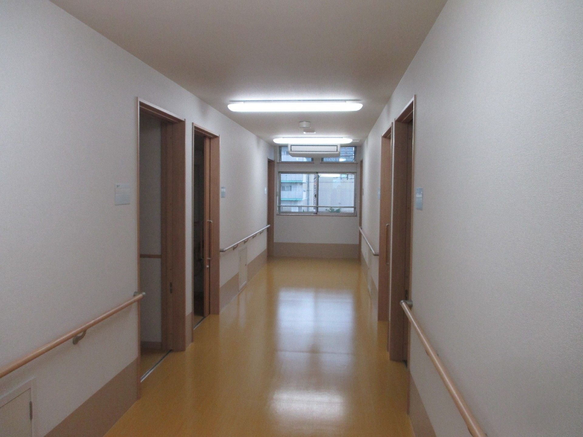 両サイドにある部屋が開け放たれ、バリアフリーであることがよく分かる廊下。手すりも両サイドに設置されている。