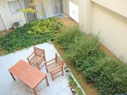 植え込みに囲まれ、テーブルセットが設置された中庭を上の階から見た様子