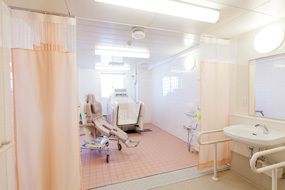 要介護の入居者様が快適に入浴できるよう、機械浴槽を設置している。脱衣所から浴室へはカーテンで仕切られている。
