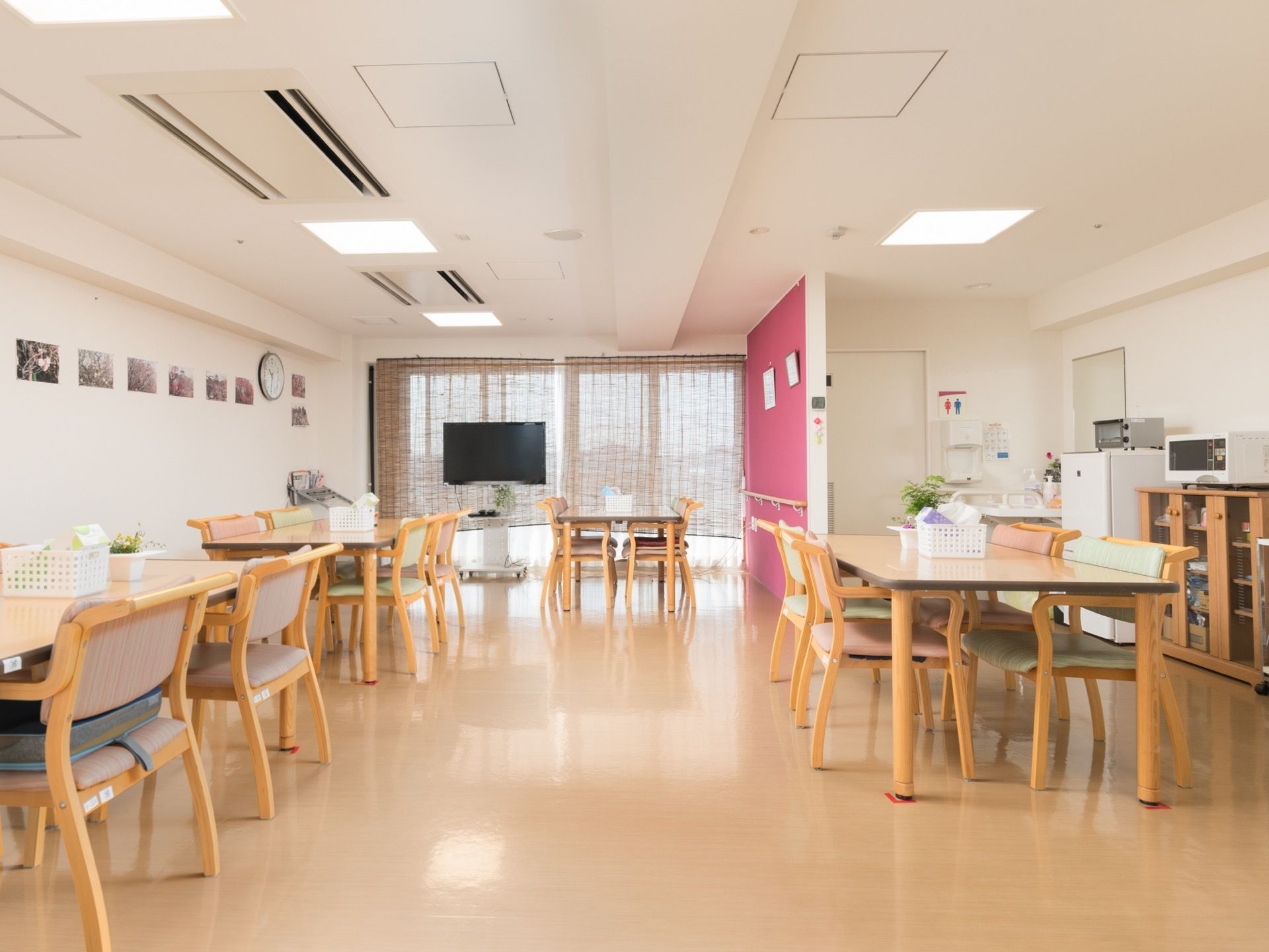 テーブルや椅子が、余裕を持って置かれている。奥にはテレビが設置されている。右の壁際には、電子レンジや冷蔵庫がある。