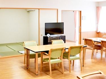 テーブルと椅子が並んだ広い食堂は、車椅子での移動も楽な空間になっている。大型テレビが設置されており、奥には和室がある。