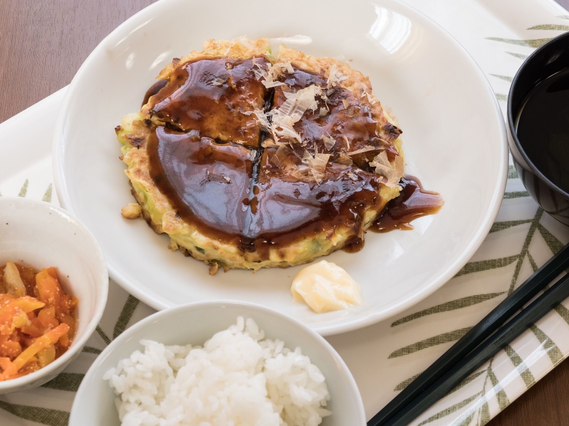 ある日の給食である。関西風お好み焼き、ニンジンの胡麻和え、お吸い物、白ご飯である。野菜をふんだんに利用している。