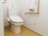 白を基調とした明るいきれいなトイレである。手すりや非常時の呼び出しブザーが完備されており、1人でも安心して利用できる。