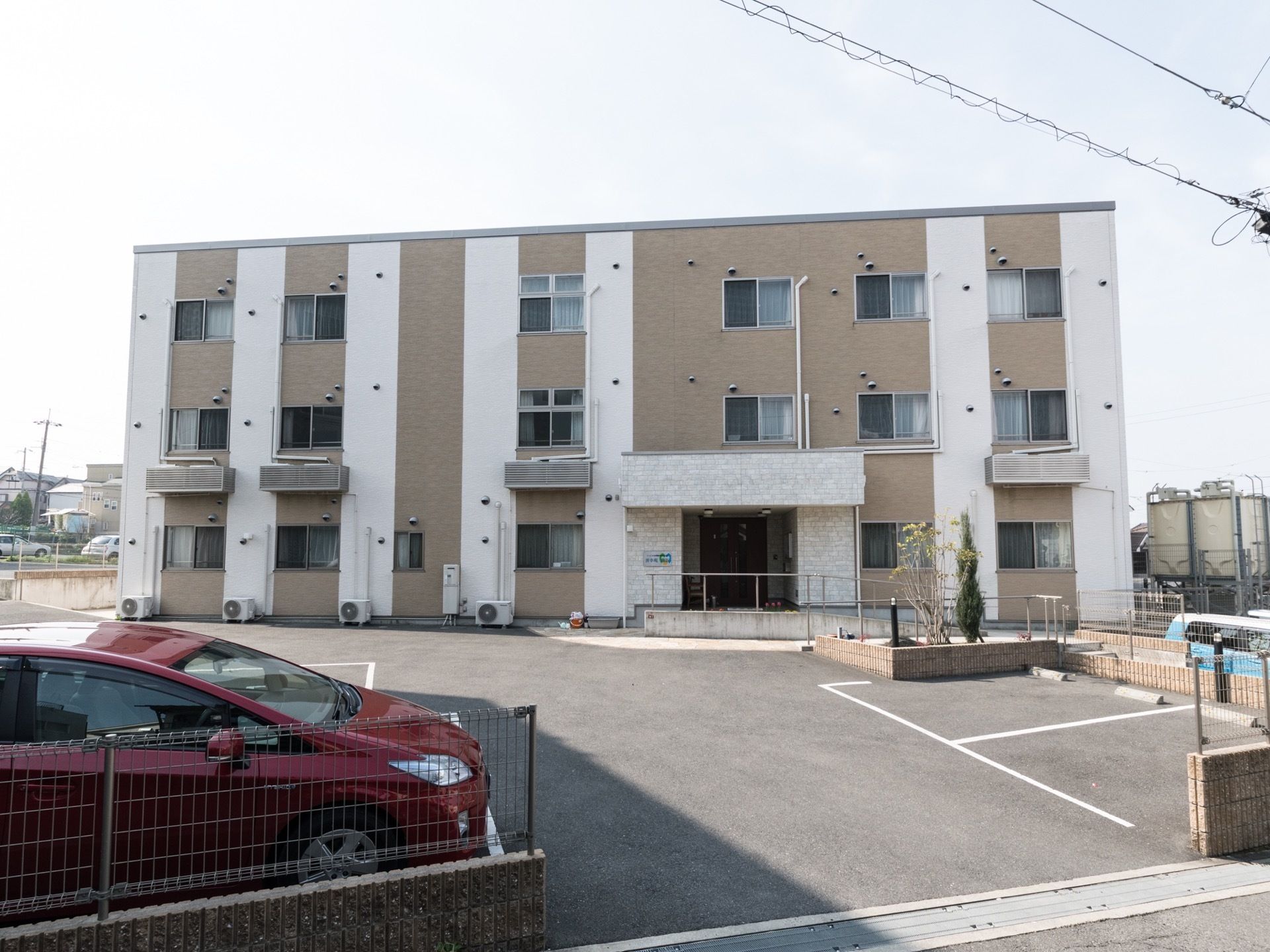3階建のモダンな建物である。周辺は広々としていて、エントランス前には駐車場が完備されているので、便利である。