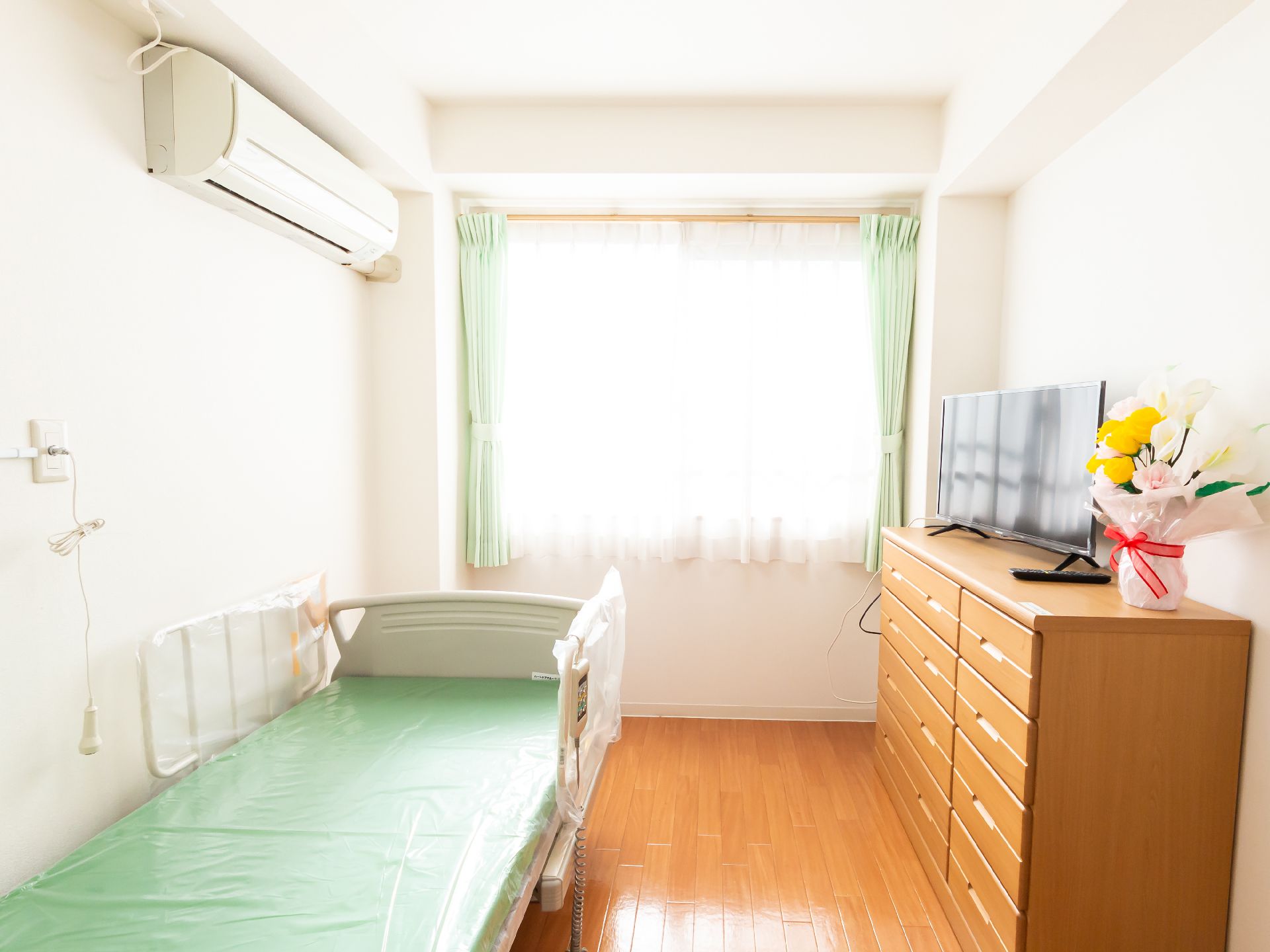 窓から日差しが降り注ぎ、介護ベッドや家具に光が当たっている居室