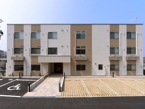 建物に沿うように駐車スペースが多数設けられている。エントランスまではスロープになっていて、車椅子をご利用の方も安心して移動することができる。