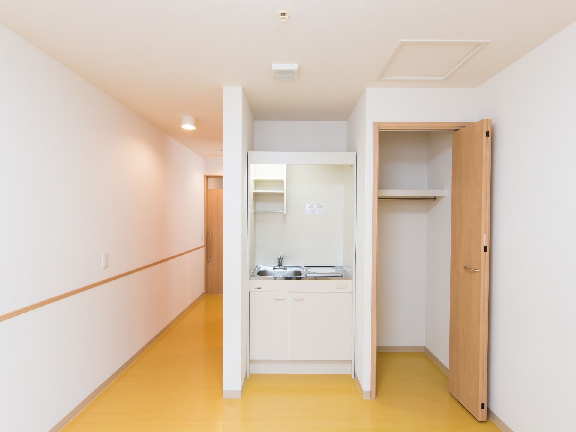 居室にミニキッチンが設置されている。流し台とIHコンロのほか、上部に棚、下部に扉付きの収納が備えてある。