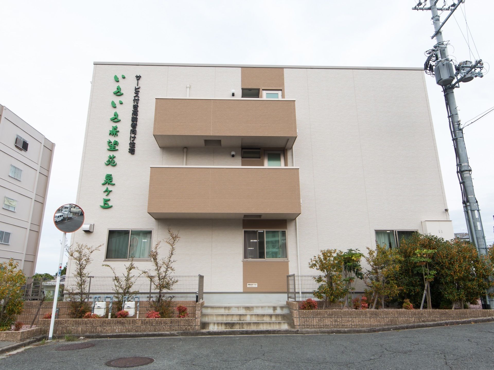 ベージュ色が基調となった３階建ての建物である。周りには木々が植えられており、自然に触れながらすごすことができる。
