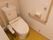 温水洗浄便座が採用された明るくきれいなトイレである。操作ボタンは便器の脇にあり、押しやすくなっている。