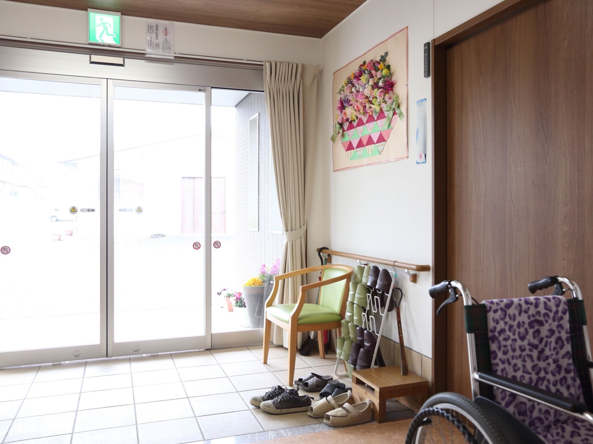 扉は自動ドアになっていて、床はバリアフリーである。入って左側の手すりの前に椅子が１脚置かれている。その横にスリッパラックがある。