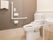 バリアフリー対応のトイレである。手すり・ナースコール・温水洗浄便座・ペーパータオルが設置され清潔感にあふれている。
