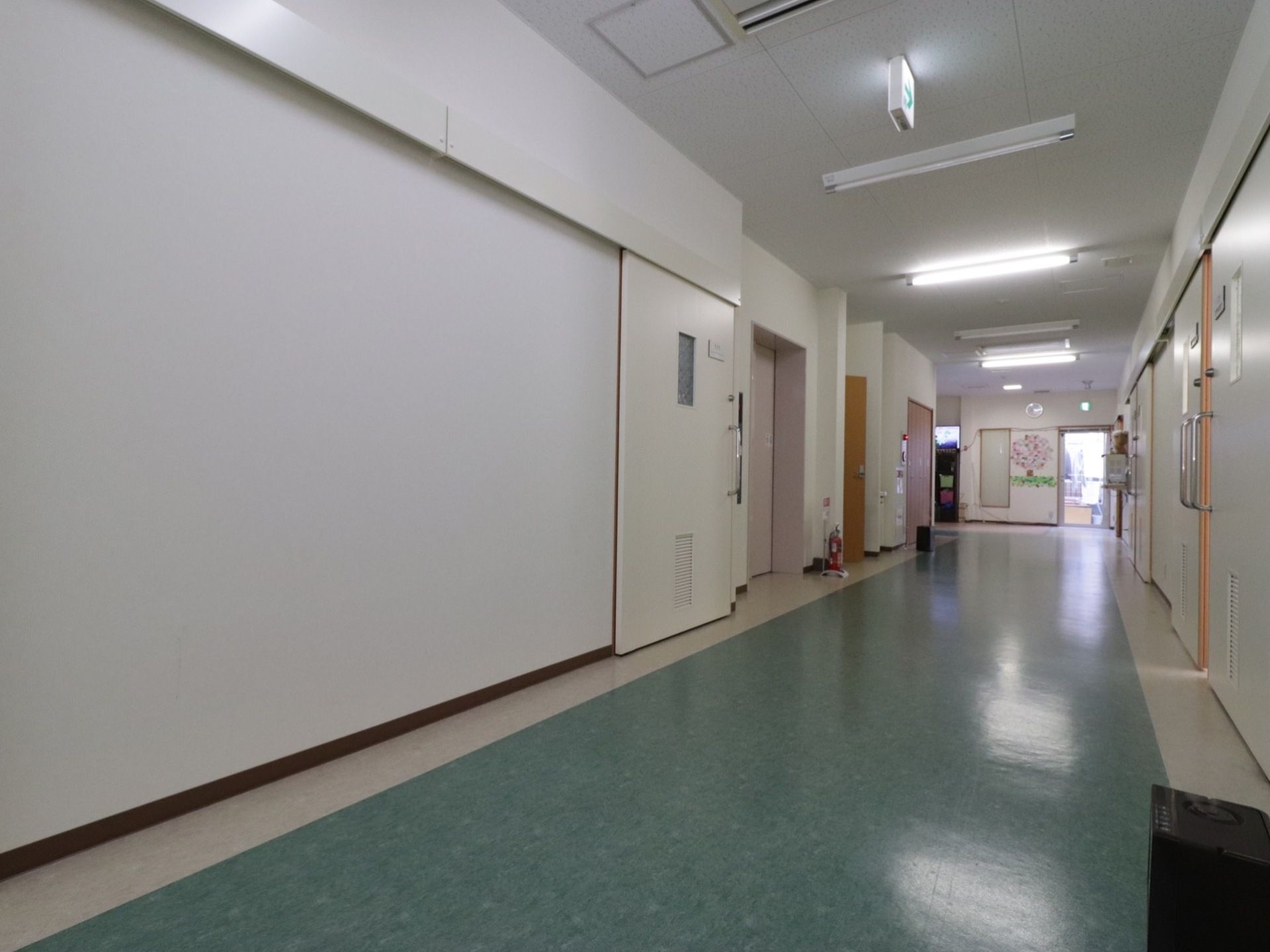 居室前の廊下である。幅を広く確保しており、車椅子をご利用の方同士のすれ違いもスムーズである。壁側には、消火器が完備されている。
