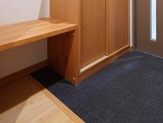 デザイン違いのフラットな床面の玄関に造り付けられた木製のベンチ