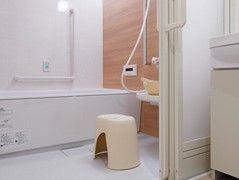 洗面台の横に浴室がある。木目調のパネルを用いた、リラックスできる環境で入浴する。浴槽の近くに操作ボタンがある。