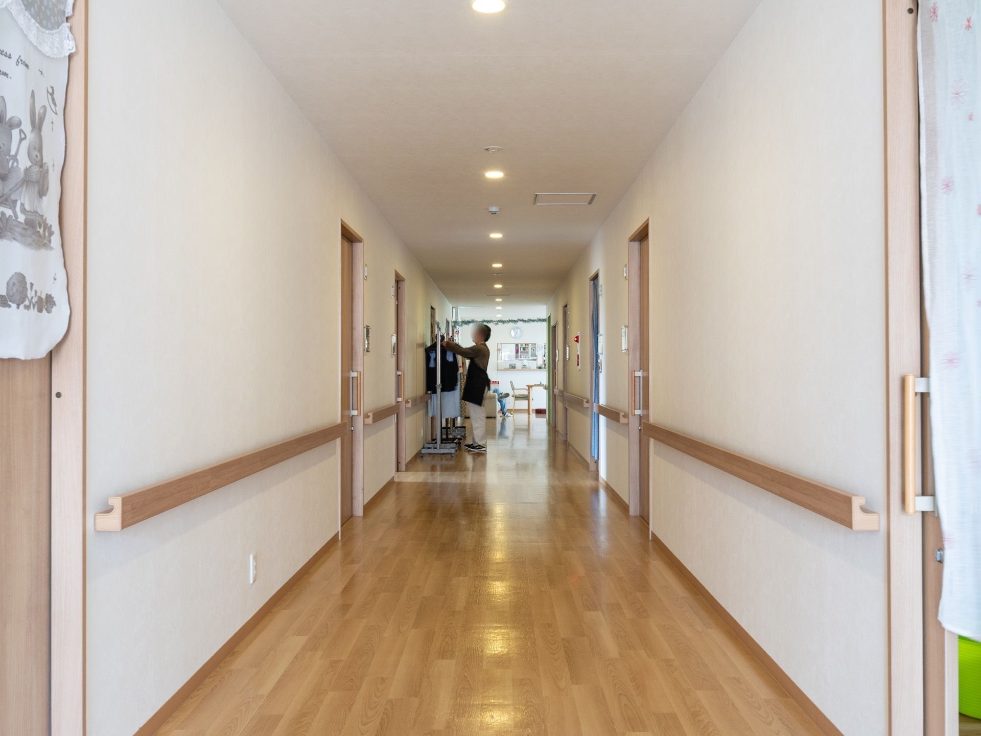 広々としたフローリングの床になっており、壁には幅が広めの木製の手すりが付いている。スタッフがハンガーラックに服をかけている。