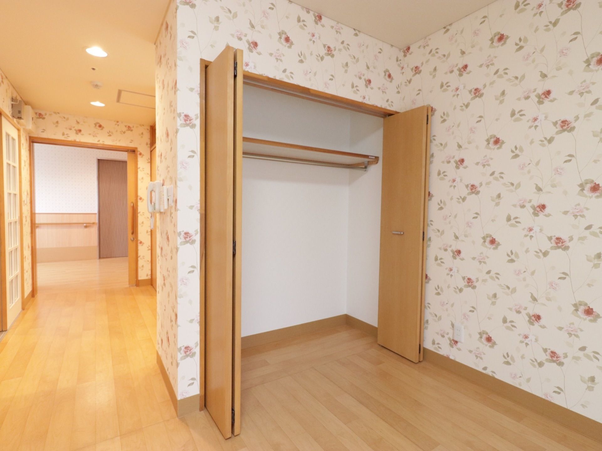 小花柄の模様があしらわれた壁に囲まれた可愛らしい部屋である。オレンジ色のあたたかい色のライトに照らされている。