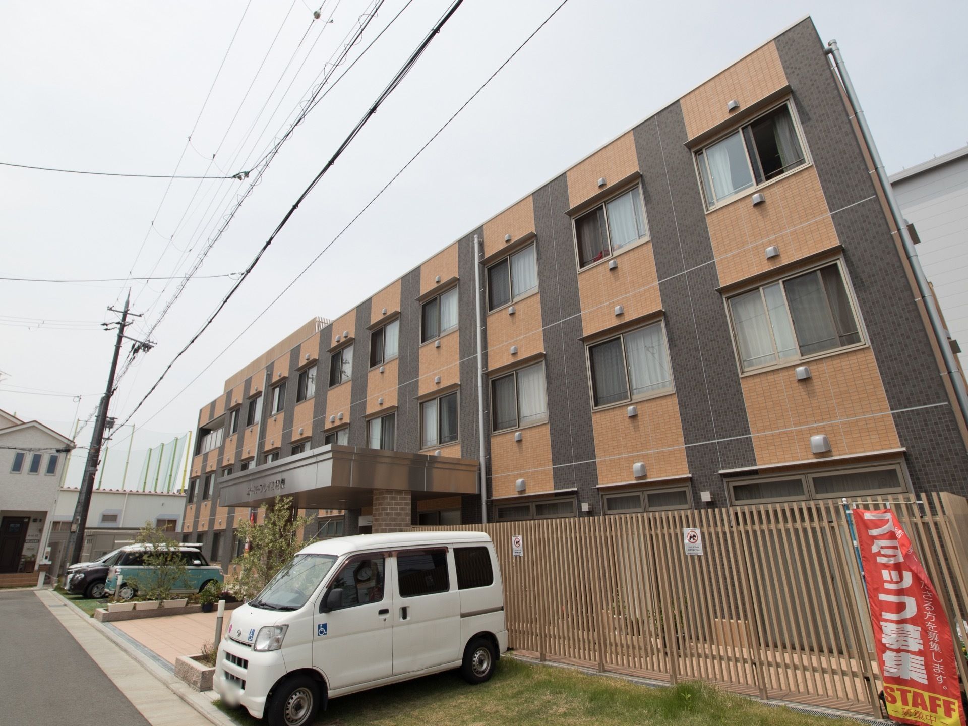 3階建ての建物で、茶色の外壁である。施設前に駐車場が完備されている。玄関前のアプローチには屋根が取り付けられている。