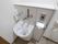 汚物流浄台の上に蛇口と洗浄ボタンとトイレットペーパーが設置されている。壁にコードの長い非常ボタンが取り付けられている。