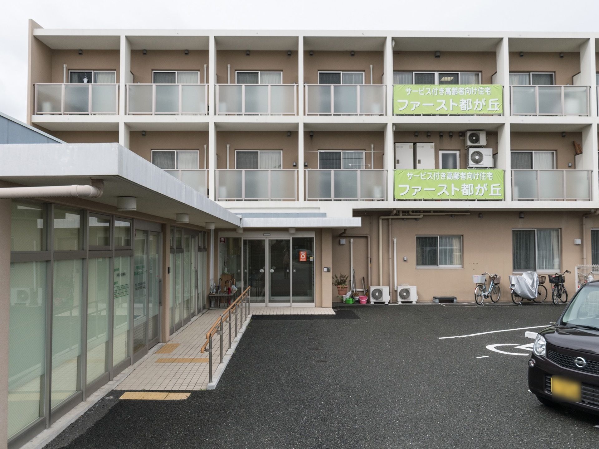温かみのあるクルミ色を基調にした建物は、カジュアルな安心感のある印象である。清掃用品や自転車などが見え、生活感がある。