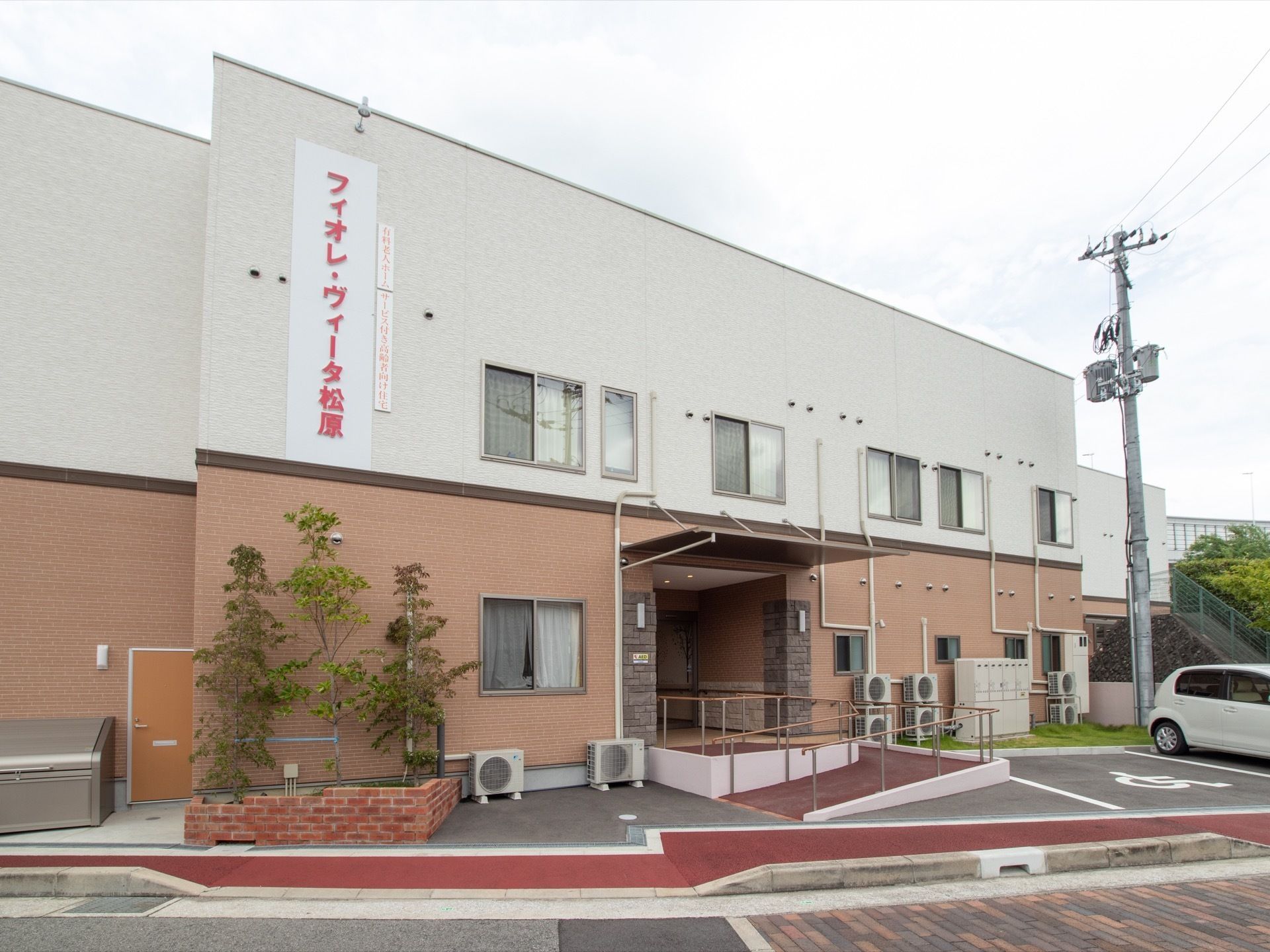 施設は２階建ての建物で、白とピンク２色の外壁になっている。２階部分には大きな文字で施設名が表示されており、わかりやすい。