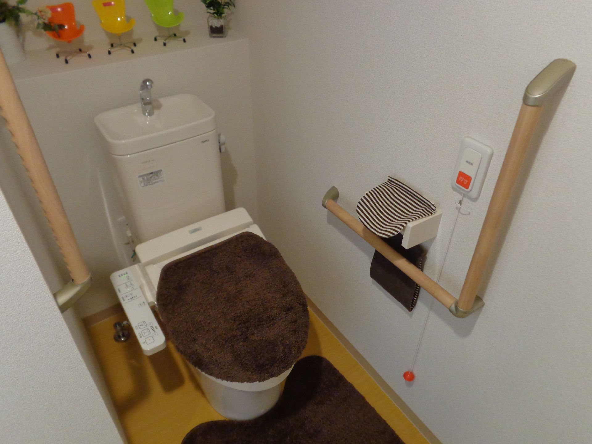 便器を挟んだ両側の壁には、それぞれＩ型とＬ型の手すりが付いている。ペーパーホルダーの近くにはナースコールがある。