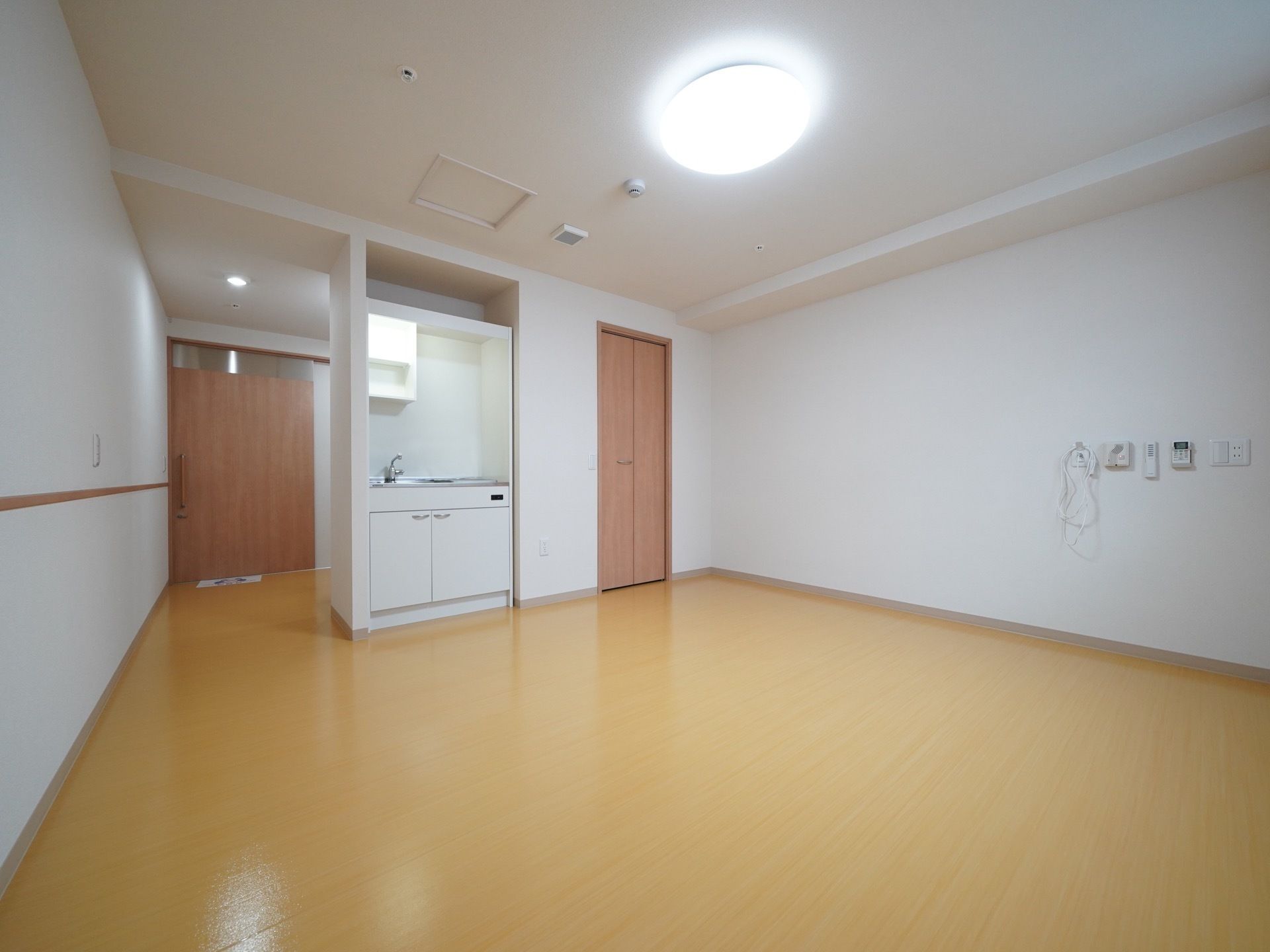 入口から室内まで段差の無い部屋である。ミニキッチンが設置されている。壁には空調のリモコンなどが取りつけられている。