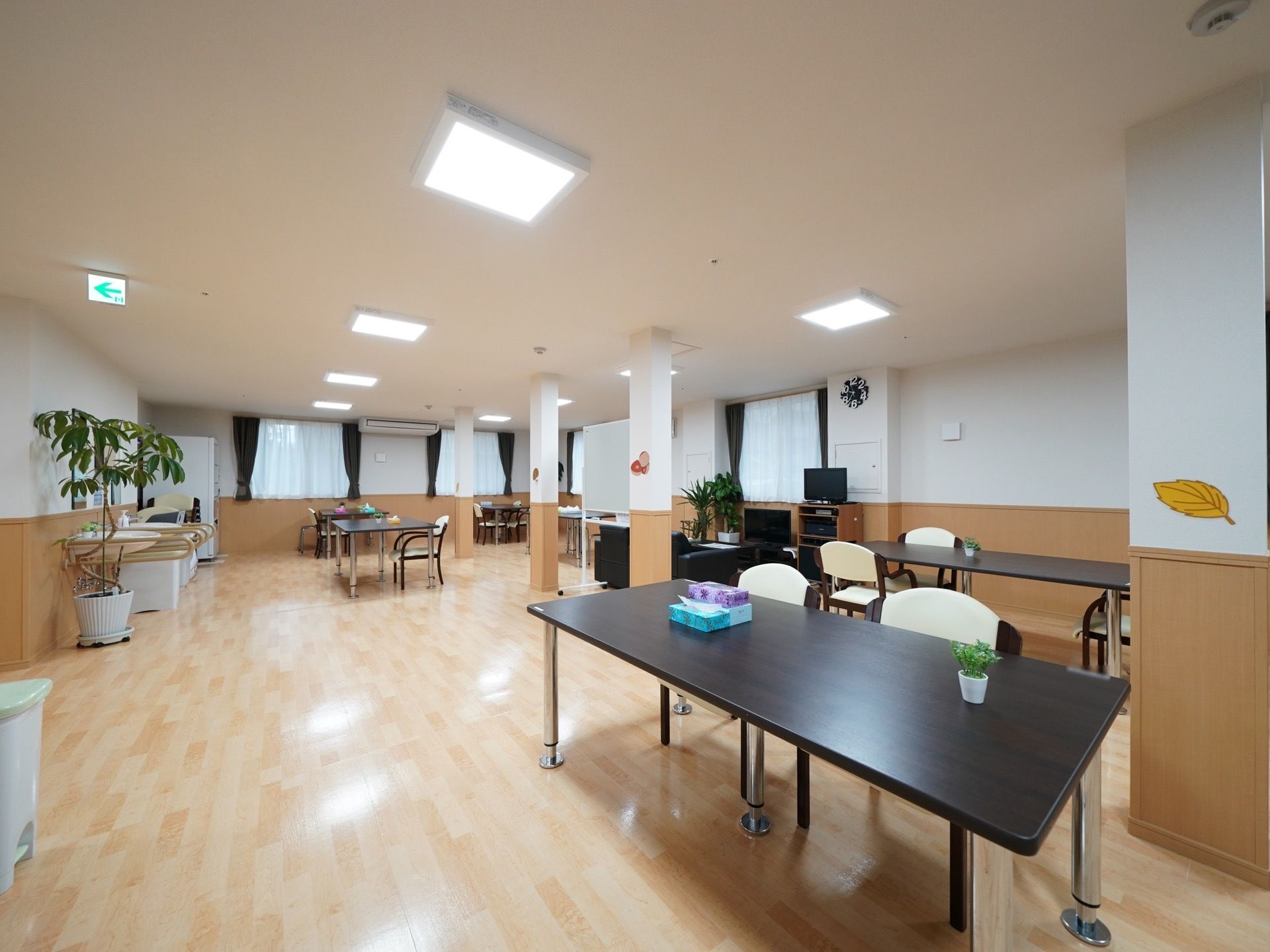 広いスペースの部屋にダイニングテーブルと椅子のセットが数組置かれている。壁際には、手すりのついた洗面台と、飲料水の自販機が設置されている。