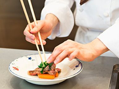 箸で皿に料理を盛り付ける様子