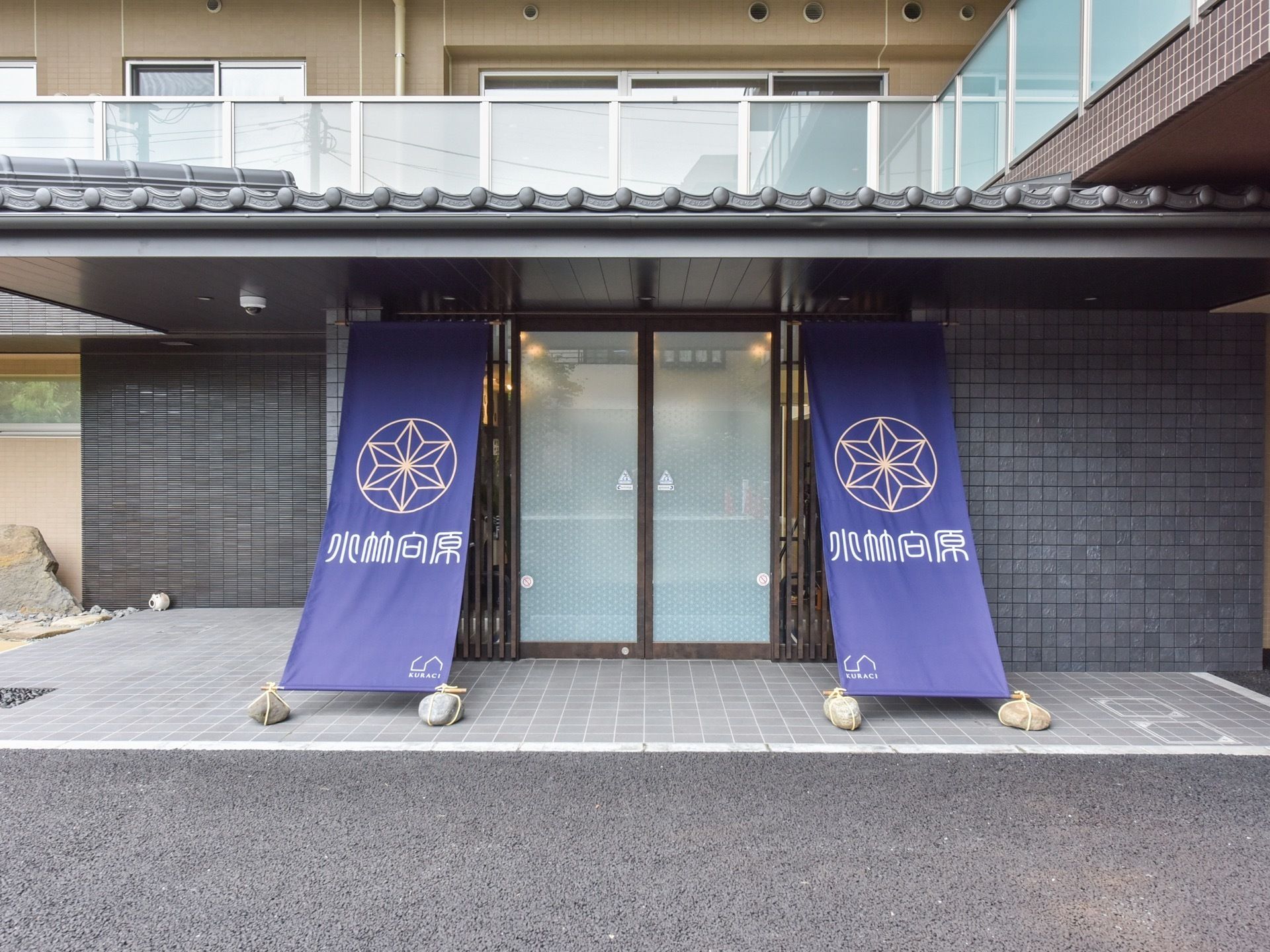 出入り口の周りはファウンテンブルーのタイル敷きになっている。出入り口は自動ドアで、左右に長のれんが下がっている。