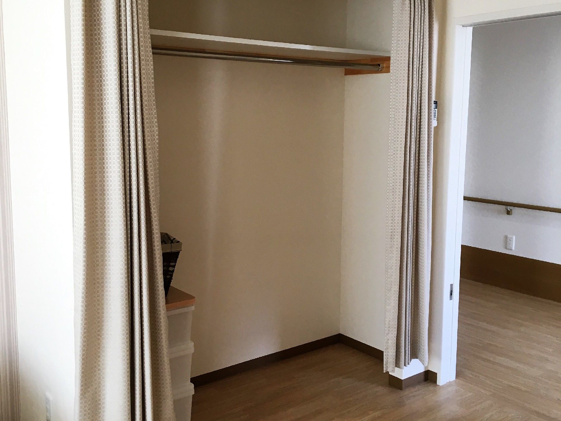 カーテンで仕切られているクローゼット風の収納。上部は棚になっている。衣装ケースがいくつか置いてある。