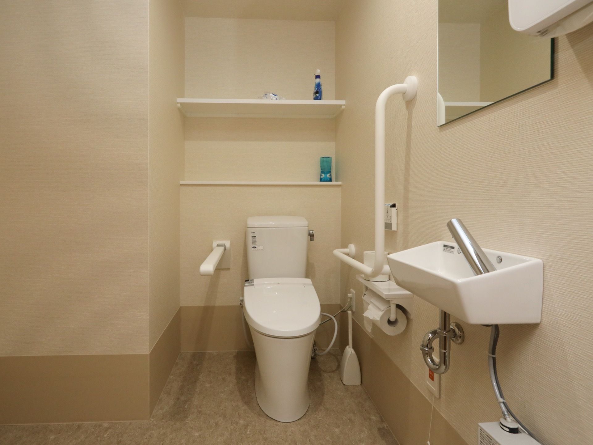 温水洗浄便座が設置された個室のトイレで、便座の裏に白い棚がある。棚の上には洗剤や芳香剤が置かれている。