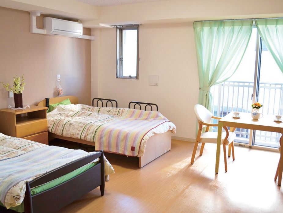 二人用の部屋にはベッドが二つ並び、入居者が持ち込んだテーブルセットや収納家具が置かれている。