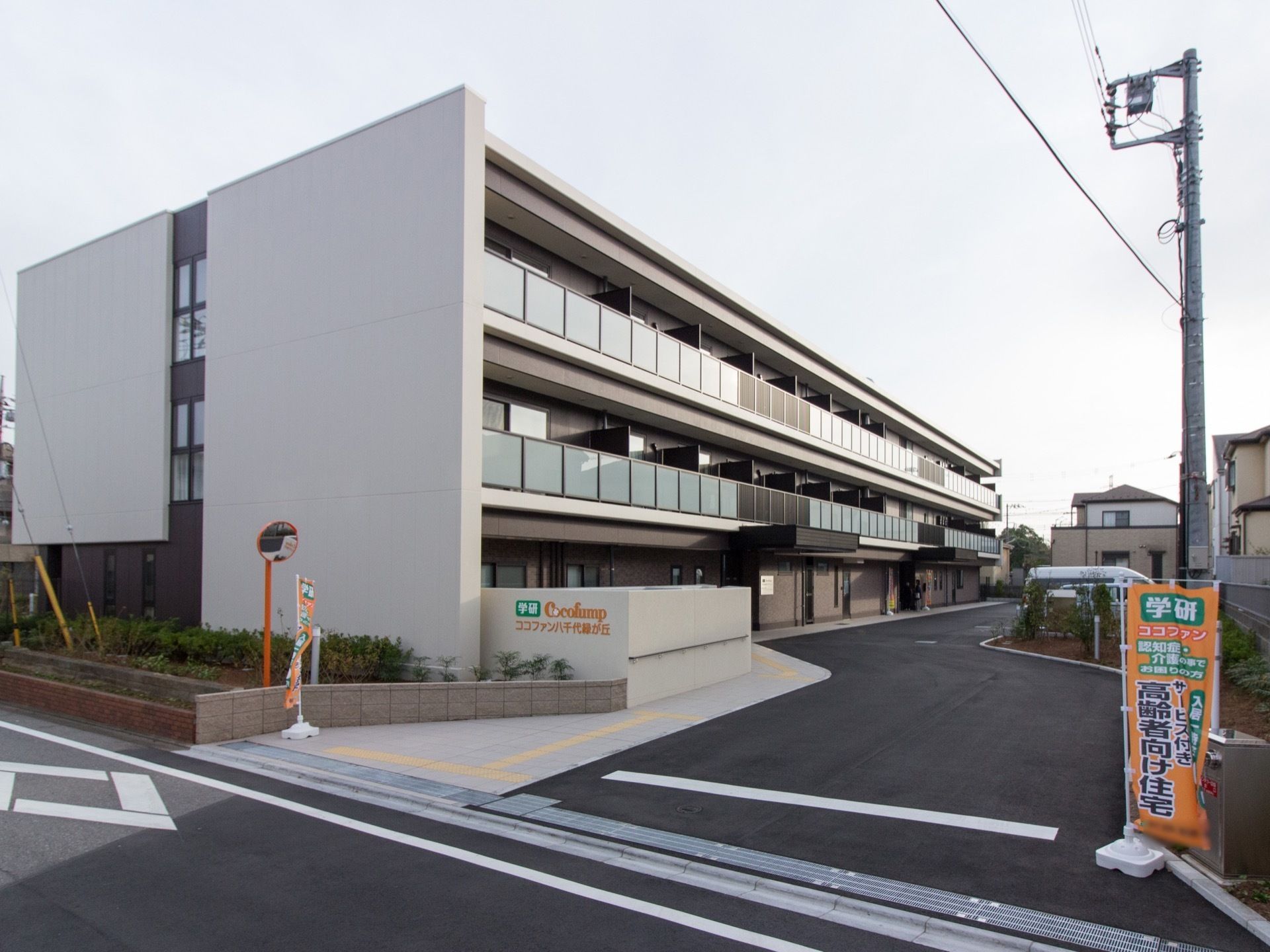 茶色と白色を基調とした３階建ての施設である。道路からの導入路が玄関に続いている。施設の名称が書かれたオレンジ色ののぼりが道路沿いにある。