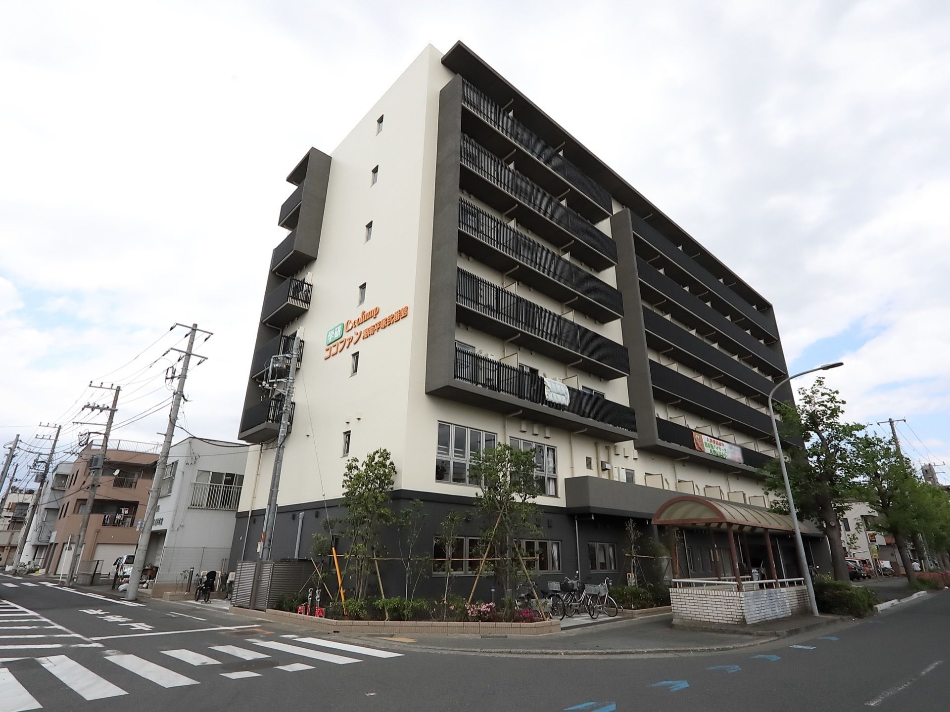 広い車道が交差する角地に建っている地上７階建ての鉄筋コンクリート造りの施設。建物の周囲に植栽が施されている。
