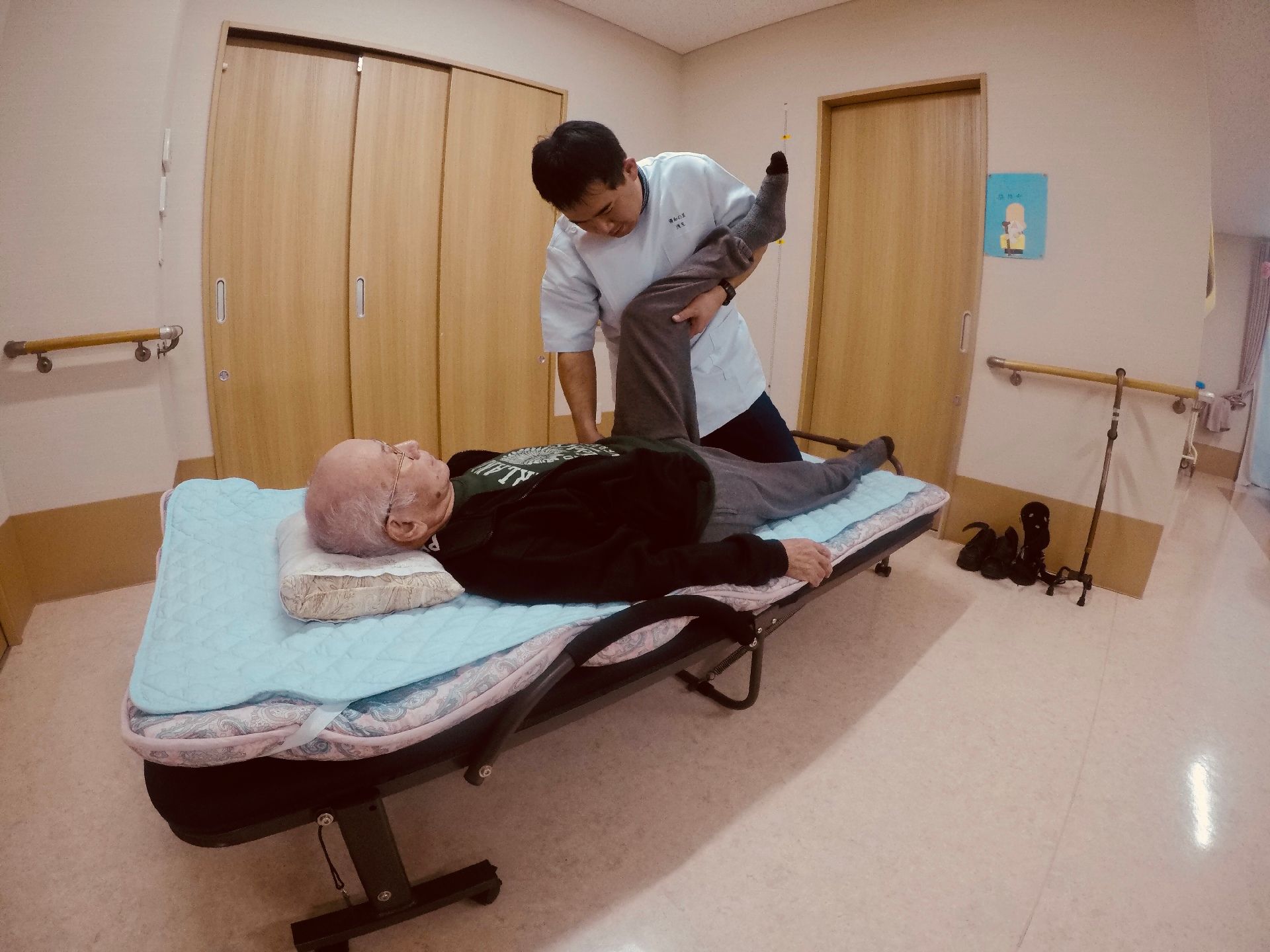 高齢の男性がベッドに横になりリハビリの施術を受けている。専門家によるリハビリプログラムが用意されているので健康的な毎日を送れる。