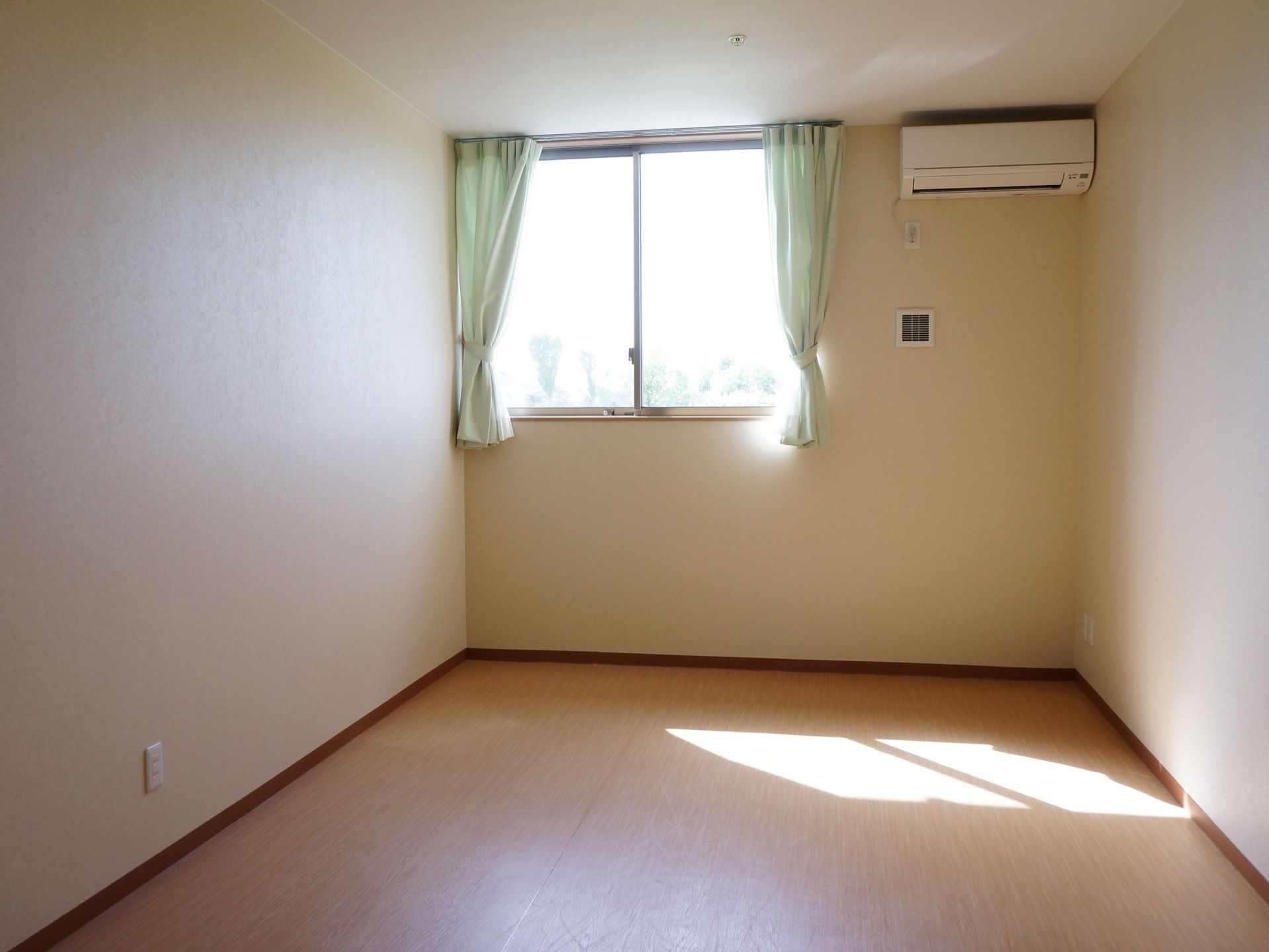 引違いの腰窓から日差しが入る居室である。窓際にはエアコンが設置さており、リモコンで自由に調整することが可能である。