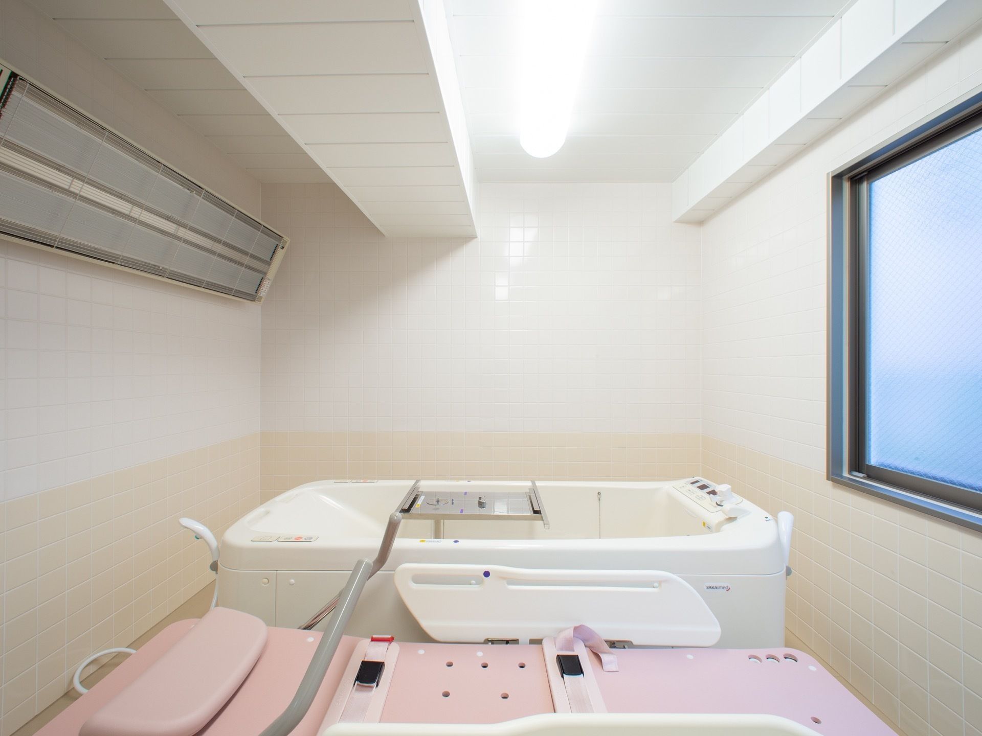 機械浴室には、専用ストレッチャーが備わった介護浴槽が完備されている。壁には、遠赤外線ヒーターがある。