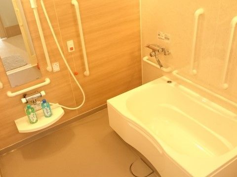 清潔感のある、木目調の壁を採用した明るい浴室である。呼び出しボタンが壁にあり、いざという時も安心である。