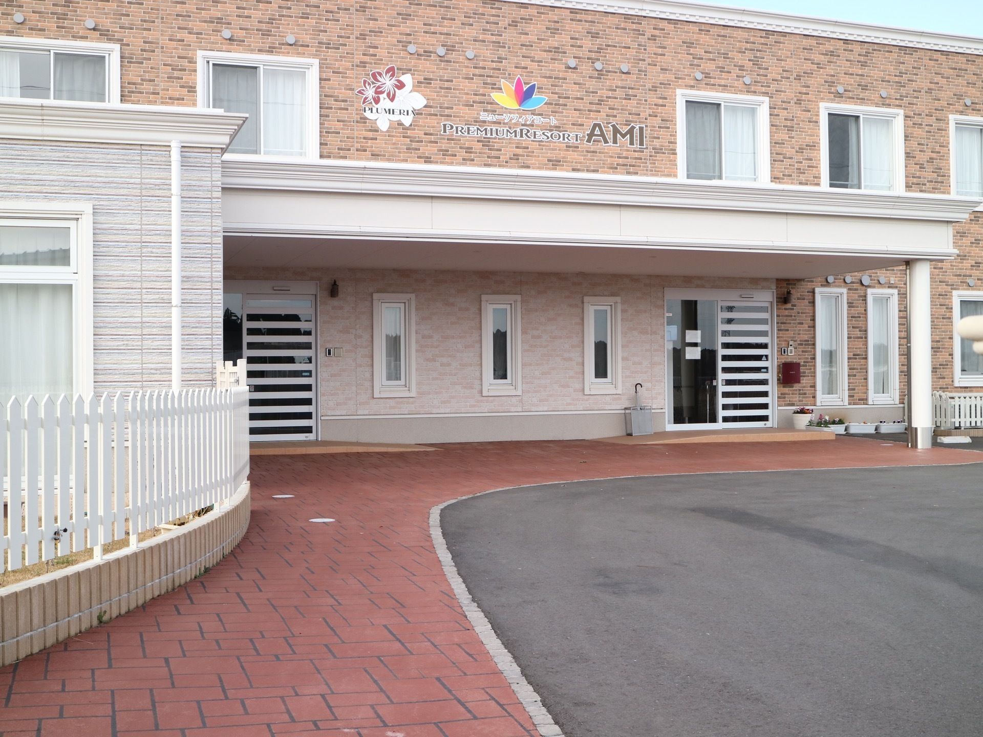 レンガ風の外壁の２階建ての建物が建っている。建物には２つの自動ドアの入口があり、それぞれの入口の前にスロープが設置されている。
