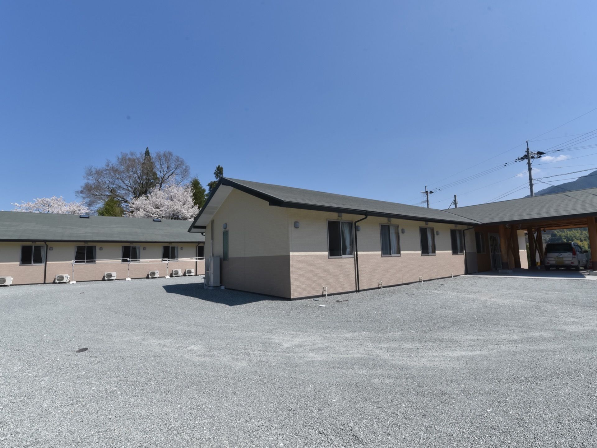 施設は広々とした敷地に平屋建てで建てられている。外壁はブラウンとベージュを基調とした落ち着いたデザインになっている。