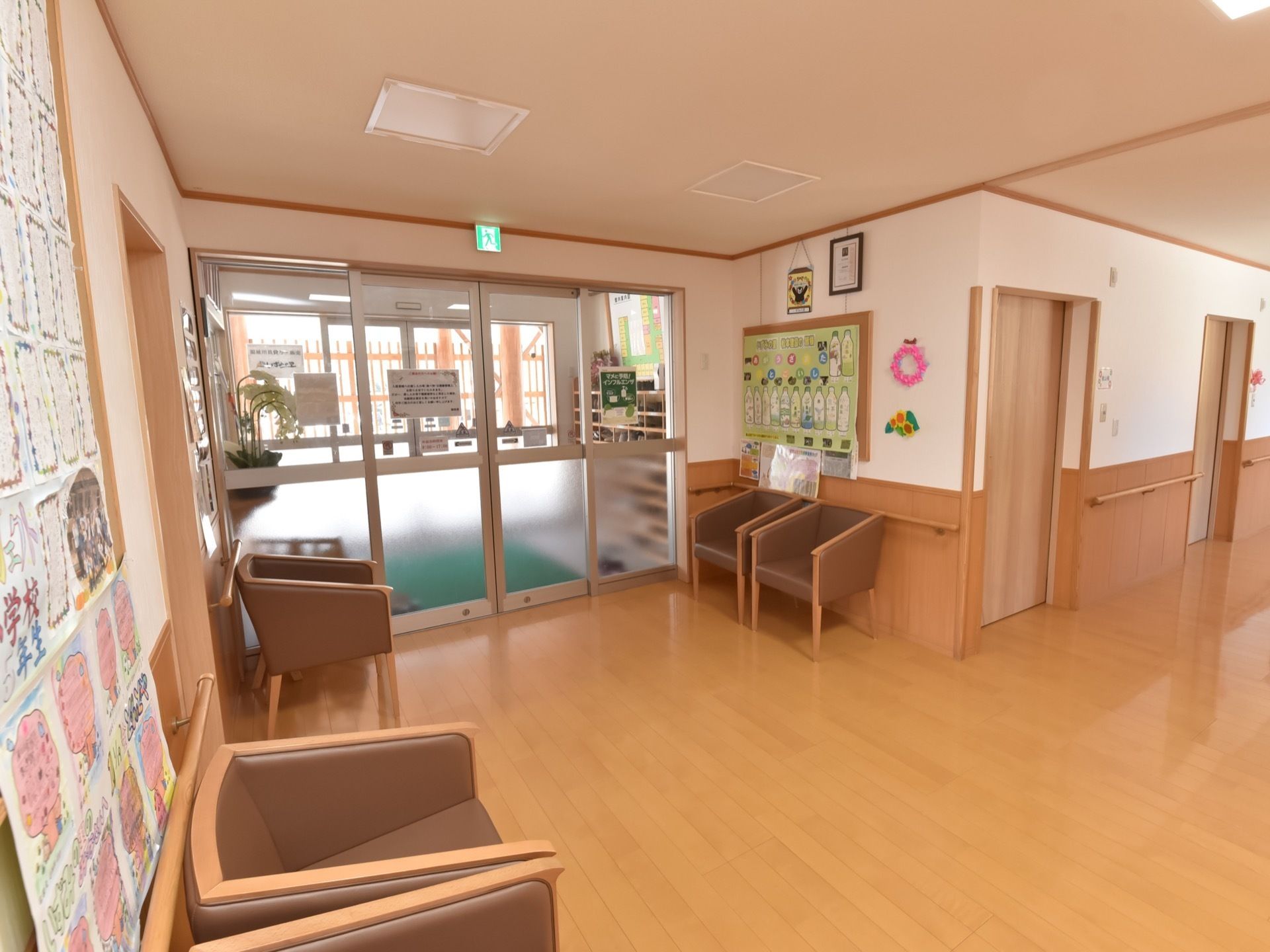 開放的な雰囲気のエントランス。ゆったりとした一人掛け用のボックス椅子が数台が置かれている。壁には掲示板が設置されている。