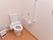 清潔感がある広々としたトイレはフローリング敷になっている。壁には緊急通報装置とL字型の手すりが取り付けられている。