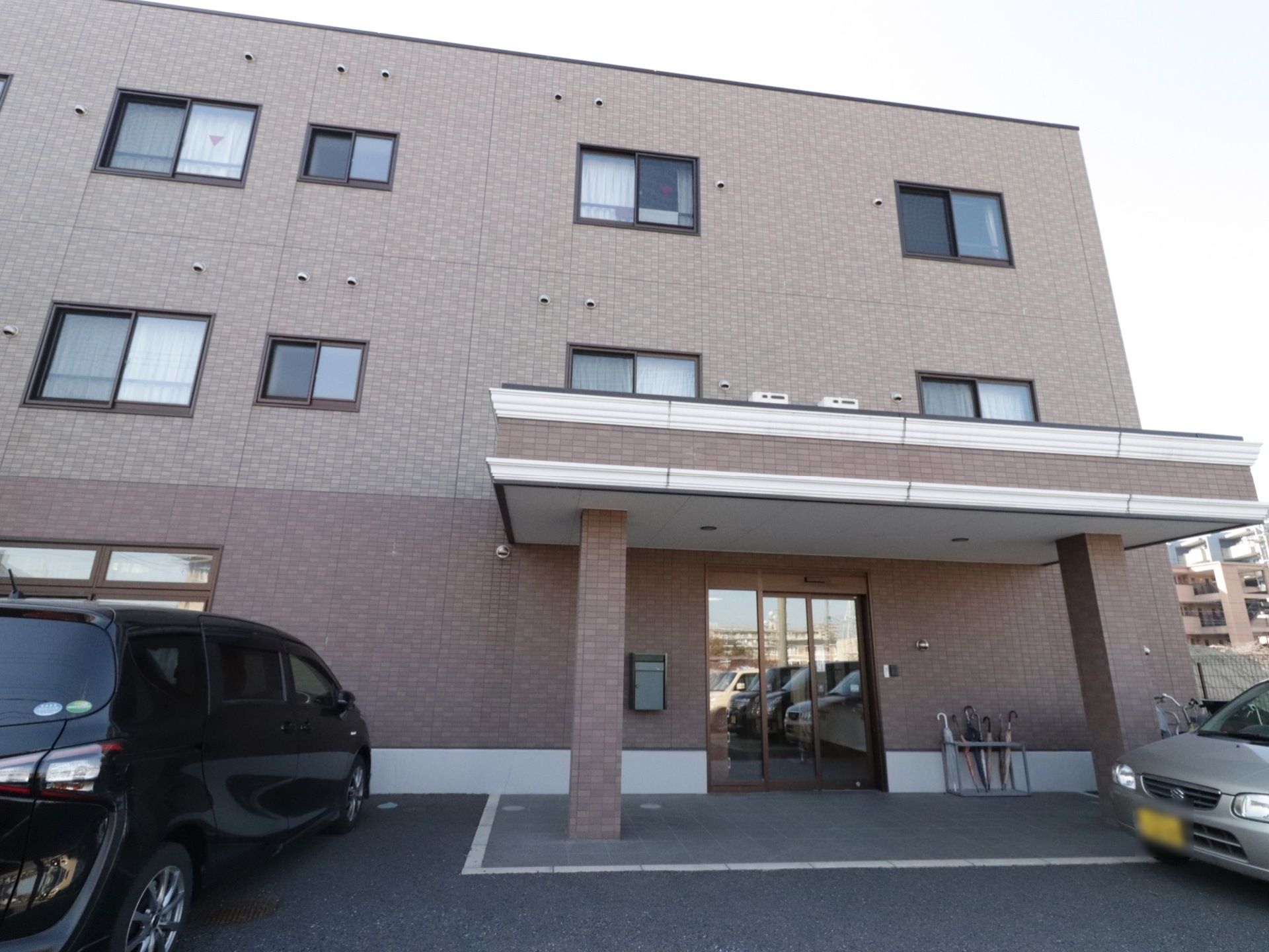 3階建ての施設の外壁は落ち着いた色合いになっている。入口には屋根が付いていて、雨の日は濡れずに車の乗降ができる。