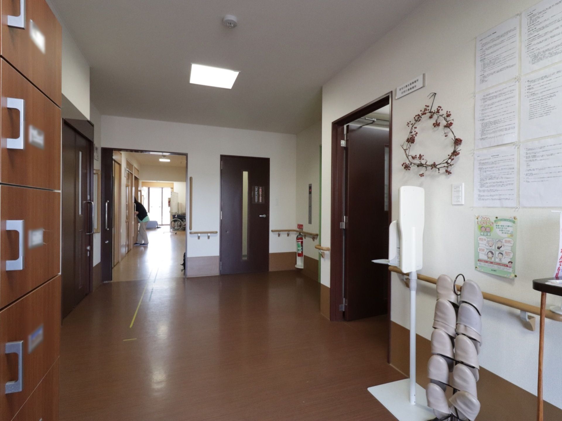 玄関フロアには扉付きの下駄箱がある。来館者用のスリッパも準備してある。扉の向こうに居室へ行く通路が伸びている。