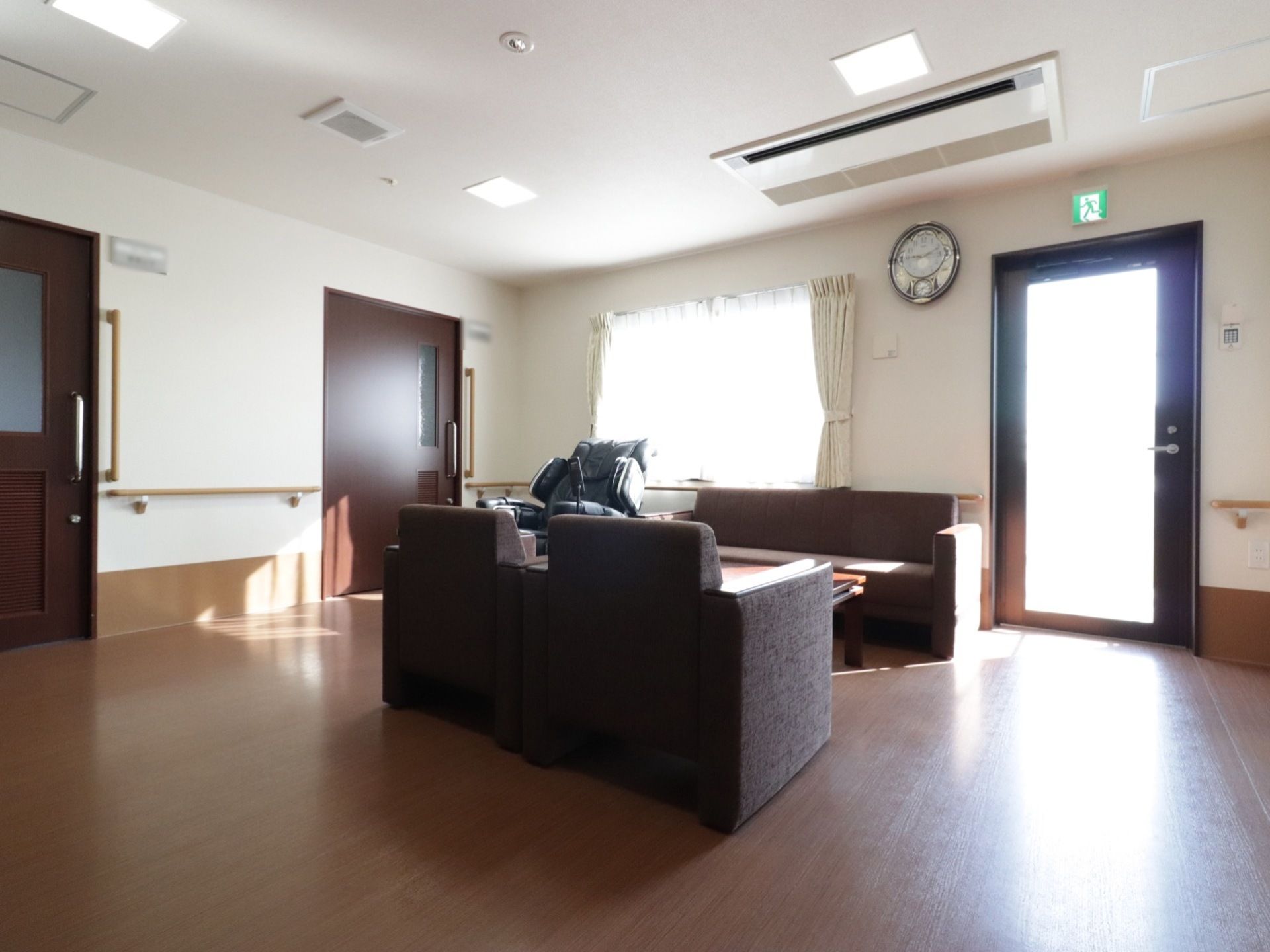 居室の扉を出たところに共有スペースがある。外へ出るドアもありる。ソファーで会話をしたり、マッサージチェアーで疲れをほぐせる。