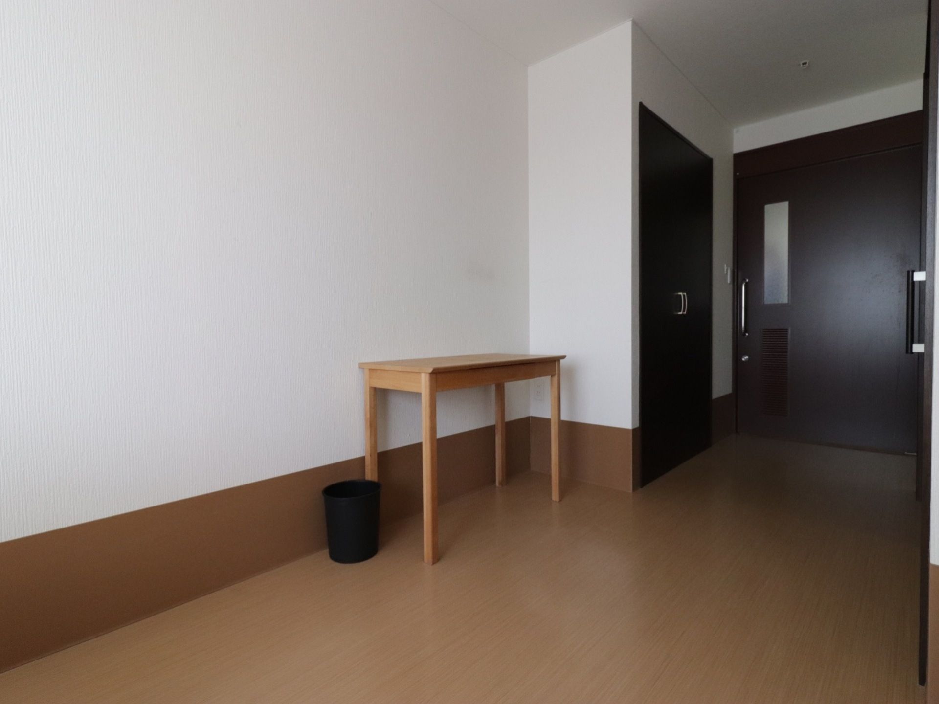 居室の入口扉は大きな引き戸になっていて通り易い、室内には両開きのクローゼットがあ、り、シンプルな木の机が置いてある。