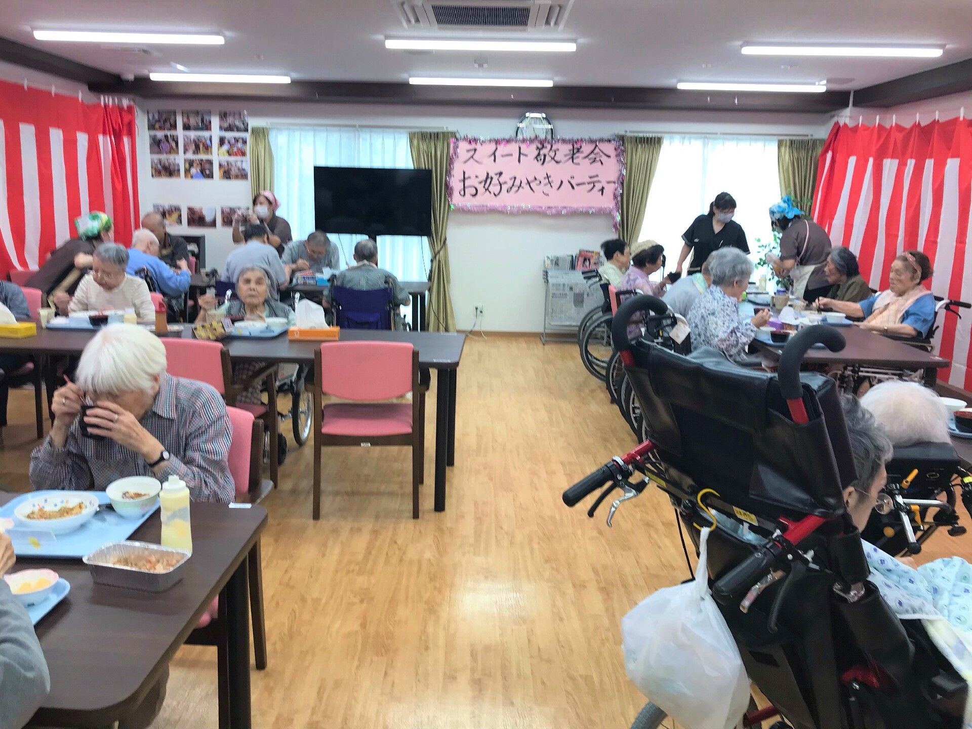 紅白の垂れ幕を飾ったイベント大会での入居者様皆さまの食事風景